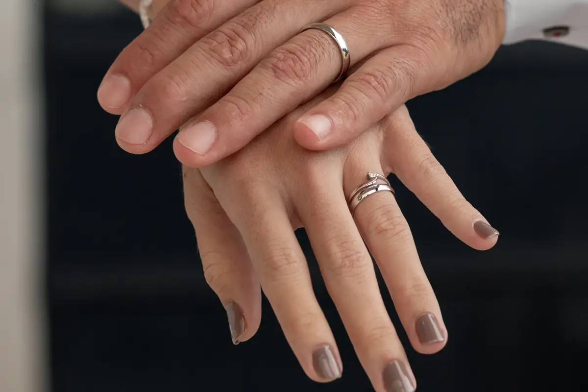 Manos de los novios, una sobre otra, con sus argollas