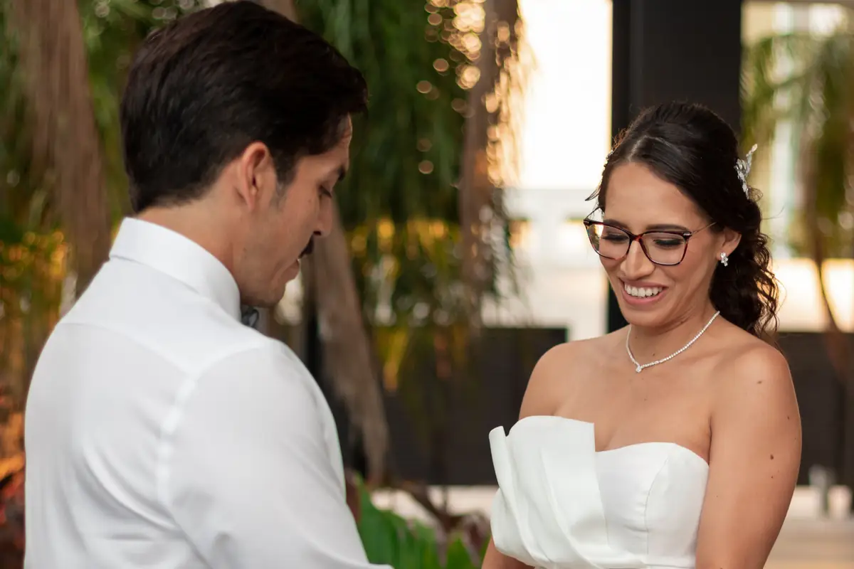 El novio toma las manos de la novia en un jardín y ella sonríe