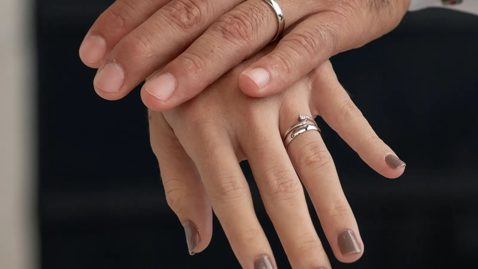 Manos de una pareja de novios, una sobre otra, con sus argollas de matrimonio
